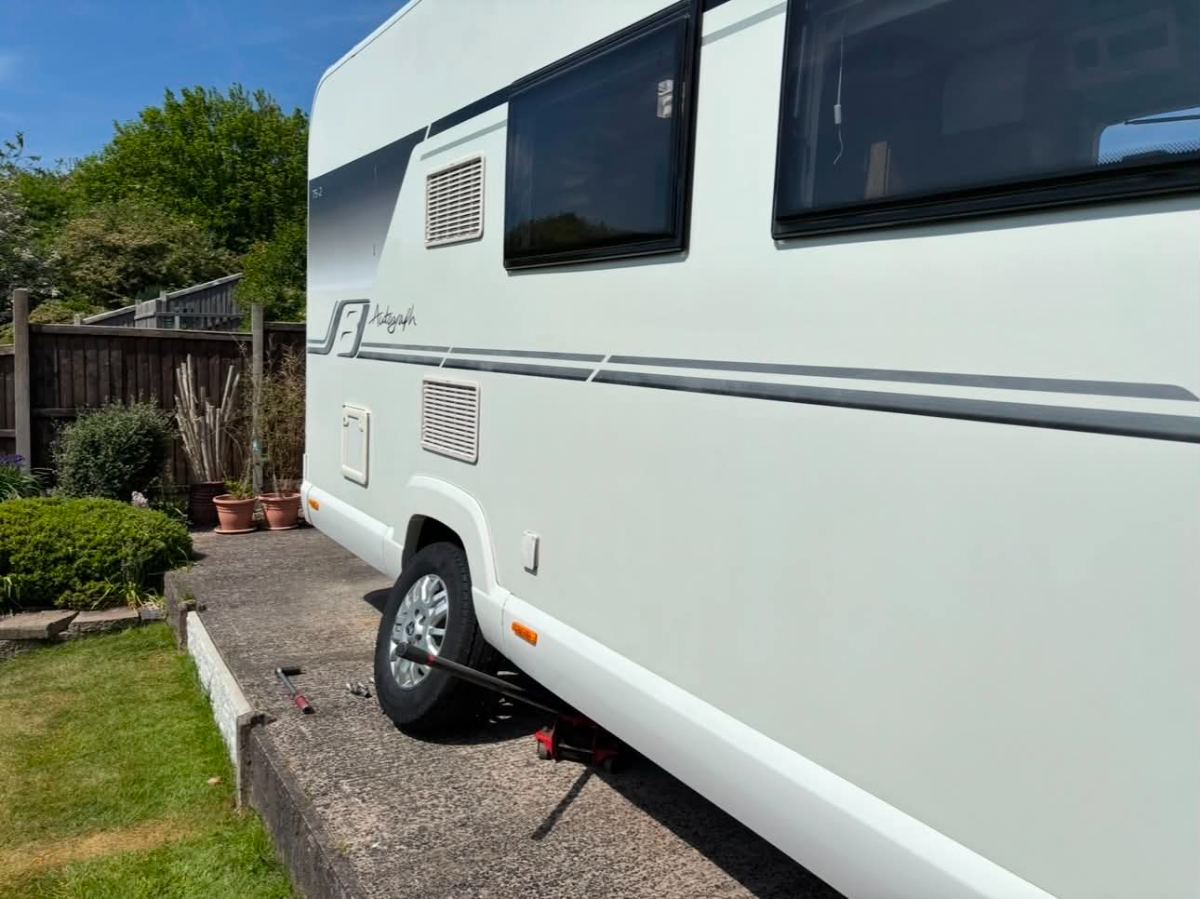 Bailey Autograph motorhome on a garden driveway with the wheel off and tools laid out