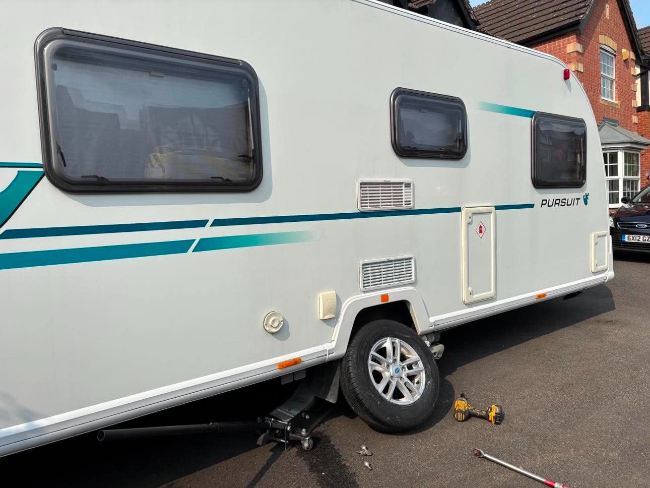 Bailey Pursuit touring caravan jacked up on a driveway with the wheel removed