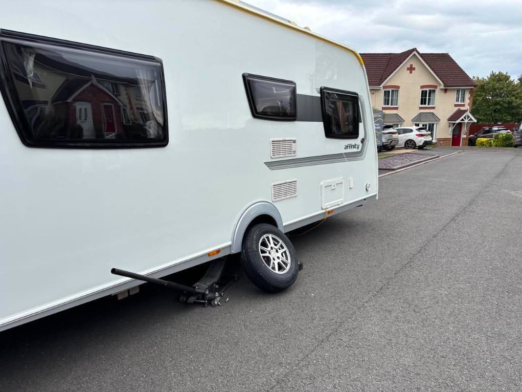 Affinity caravan jacked up on a residential road with the wheel off