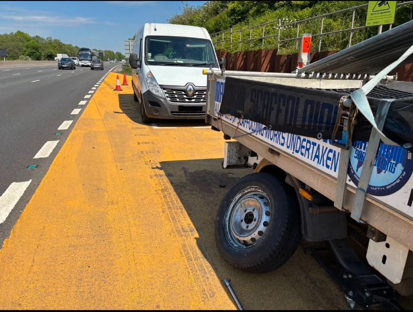 DMS Tyres van with cones set out on the M6 hard shoulder near junction 13, changing a tyre on a scaffolding trailer