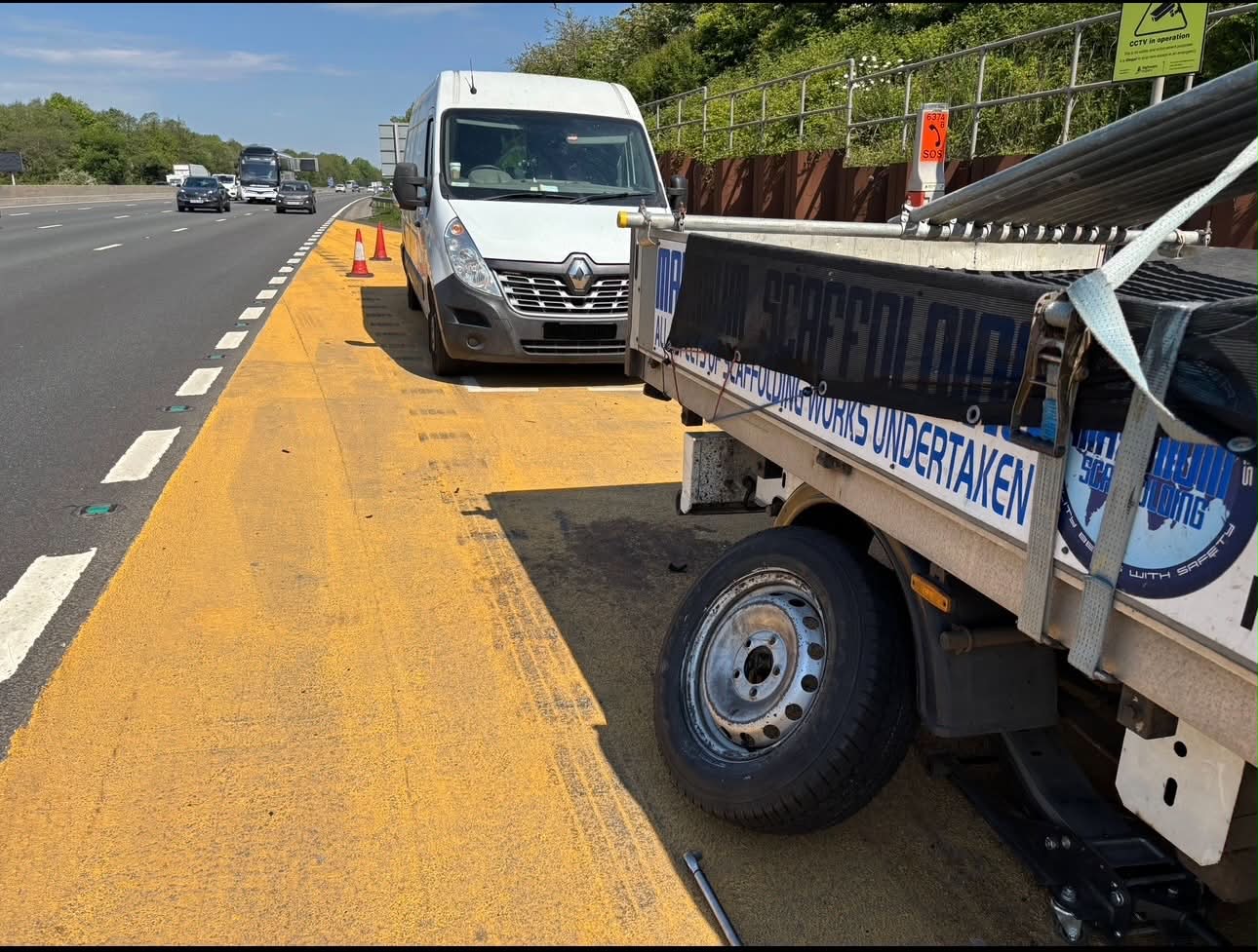 DMS Tyres van with cones set out on the M6 hard shoulder near junction 13, changing a tyre on a scaffolding trailer